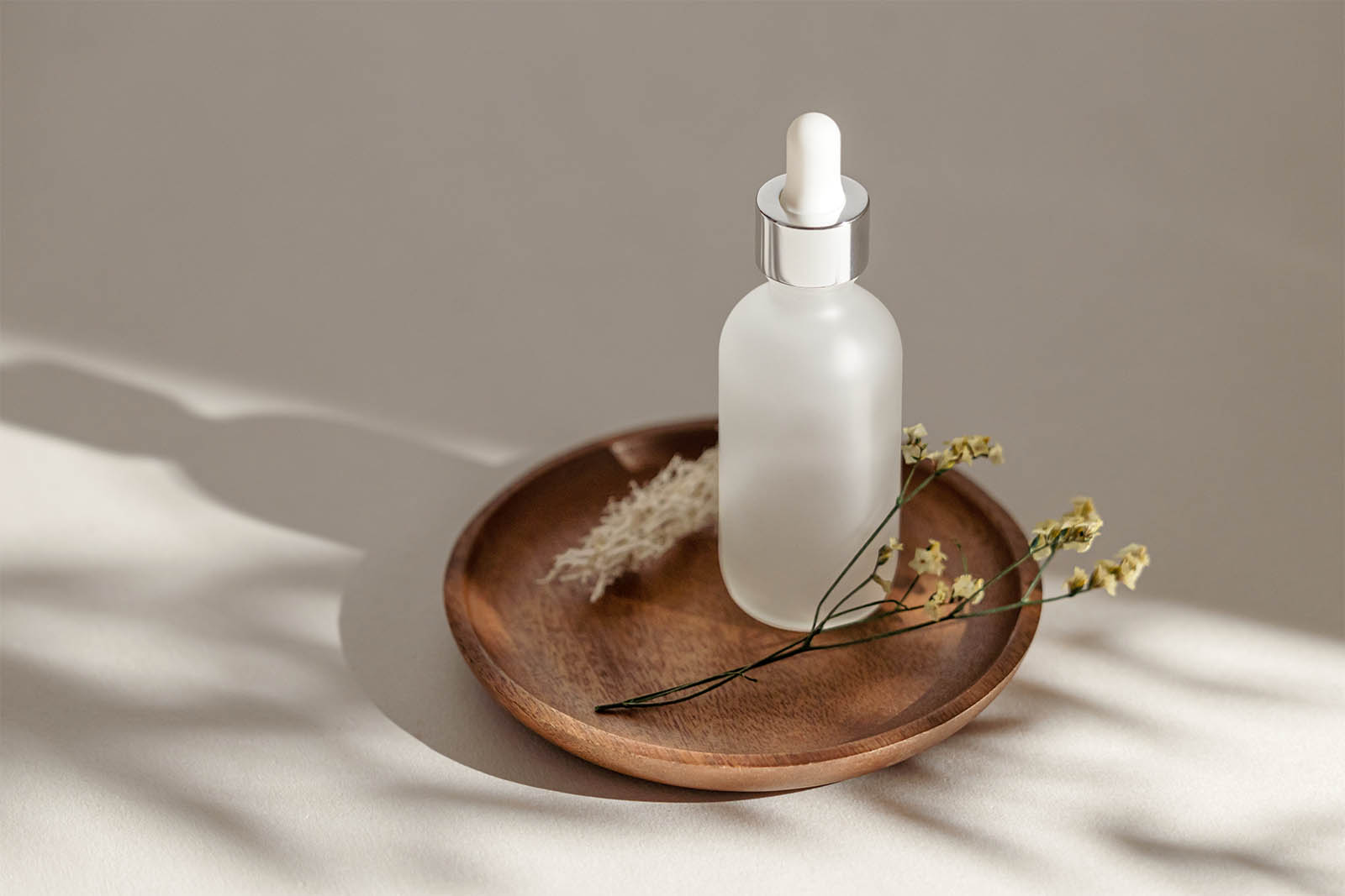 Frosted dropper bottle on wooden tray mockup